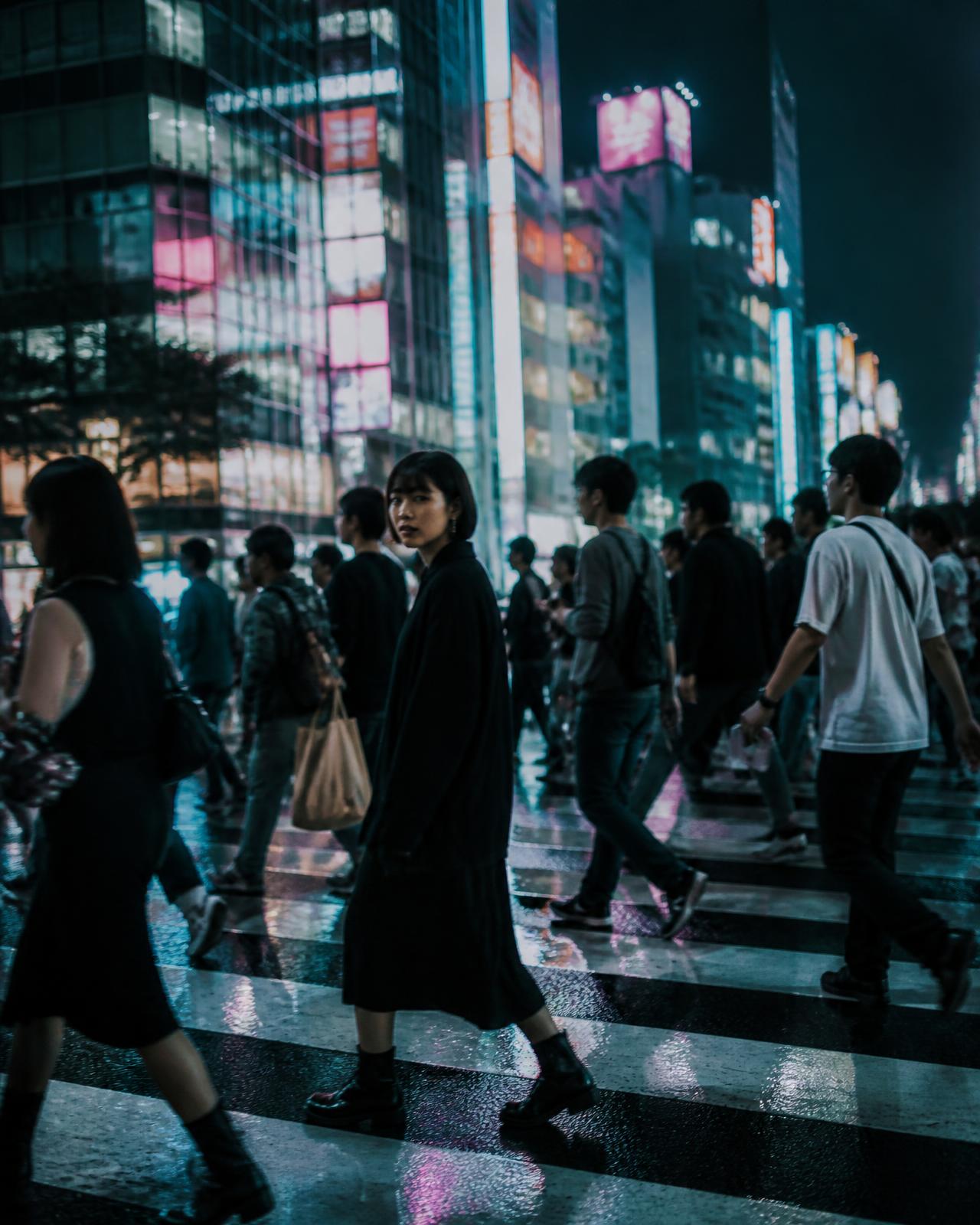 Crowds crossing a neon-lit Shibuya street at night